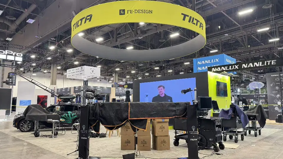 Tilta booth under yellow ring sign with camera rigs, video screen and boxes on floor