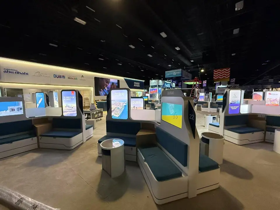 Teal meeting pods and round side tables between lit vertical displays