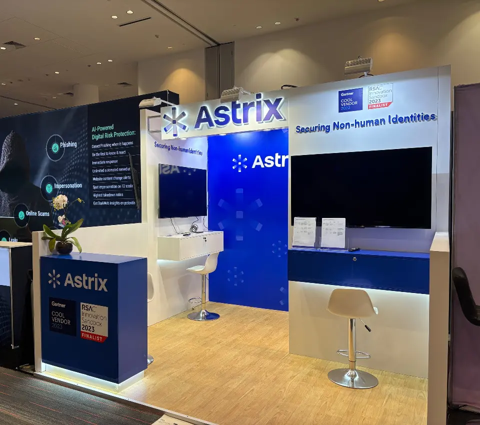 Astrix booth front with blue counter, lit Astrix sign and Securing Non-human Identities header