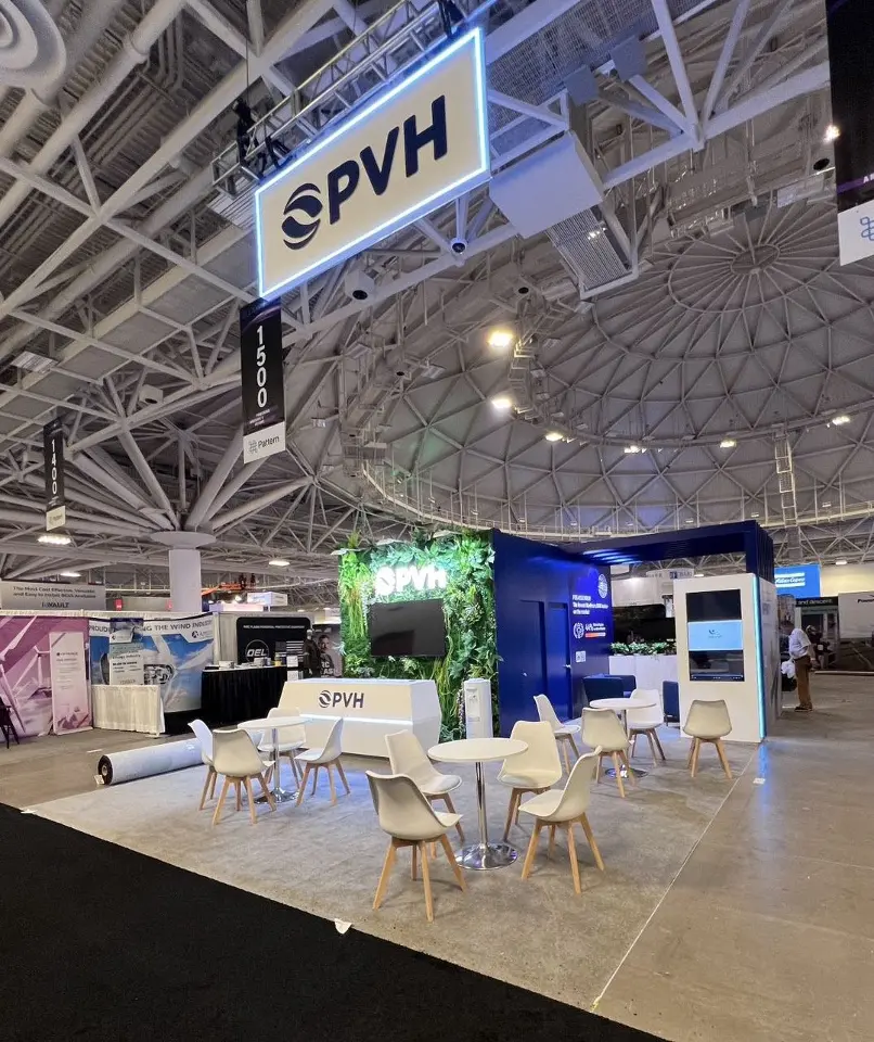 Hanging PVH sign over white tables and chairs seen from across the hall