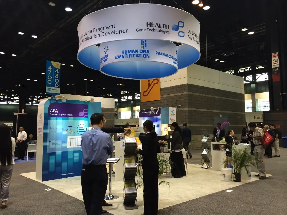 Health Gene Technologies booth with round Gene Fragment hanging sign and lit columns