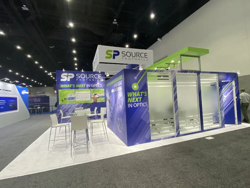 Rear angle of Source Photonics booth showing frosted meeting rooms and green canopy edge
