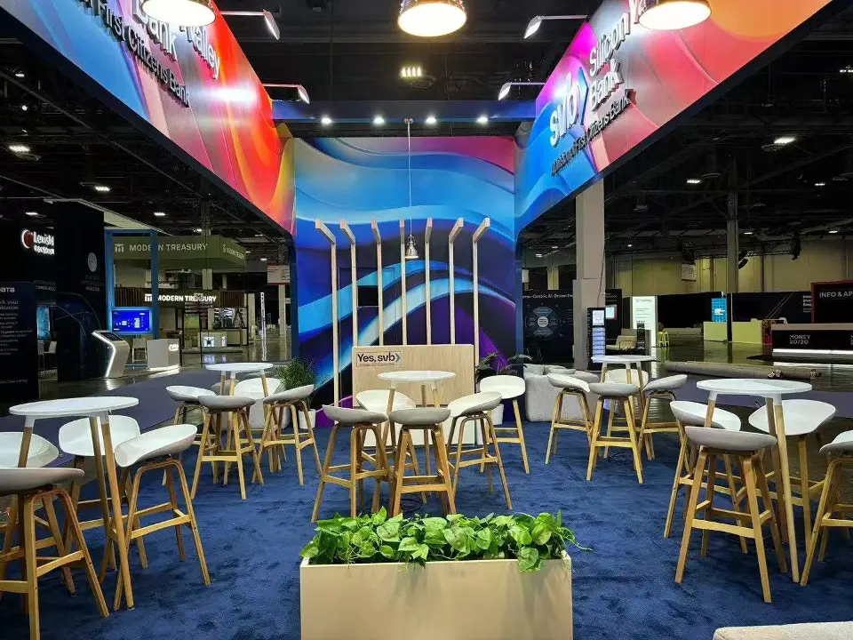 Caf&eacute; area with high tables, wood-look stools and a planter under a wave-graphic header