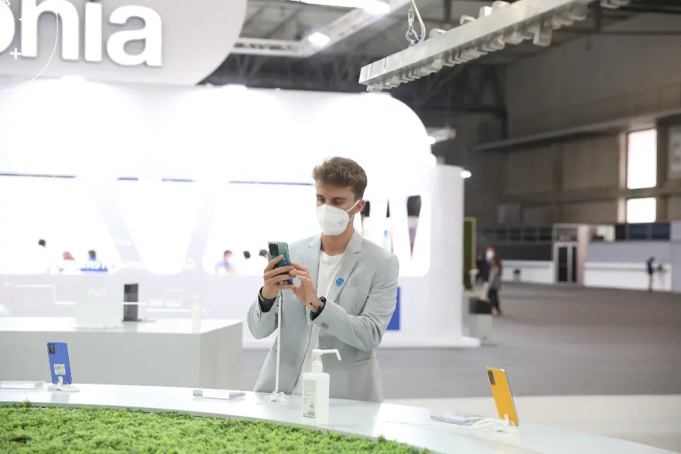 Visitor photographing a phone at the green-topped round counter under the canopy