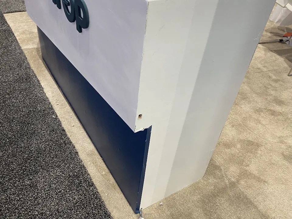 Low detail of a white wall corner with logo and teal base trim