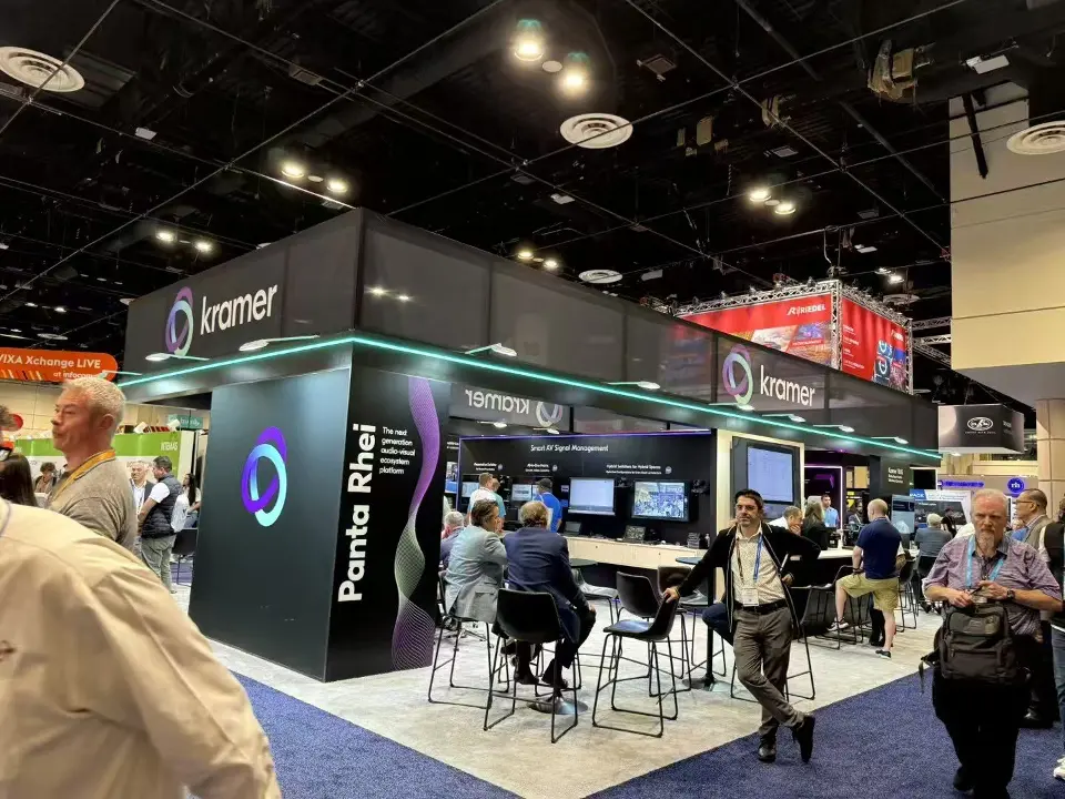 Corner of the Kramer booth with lit logo, column graphic and high tables
