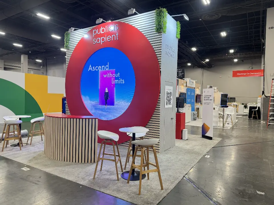 Corner with red ring around a round screen, wood-look stools and a high table