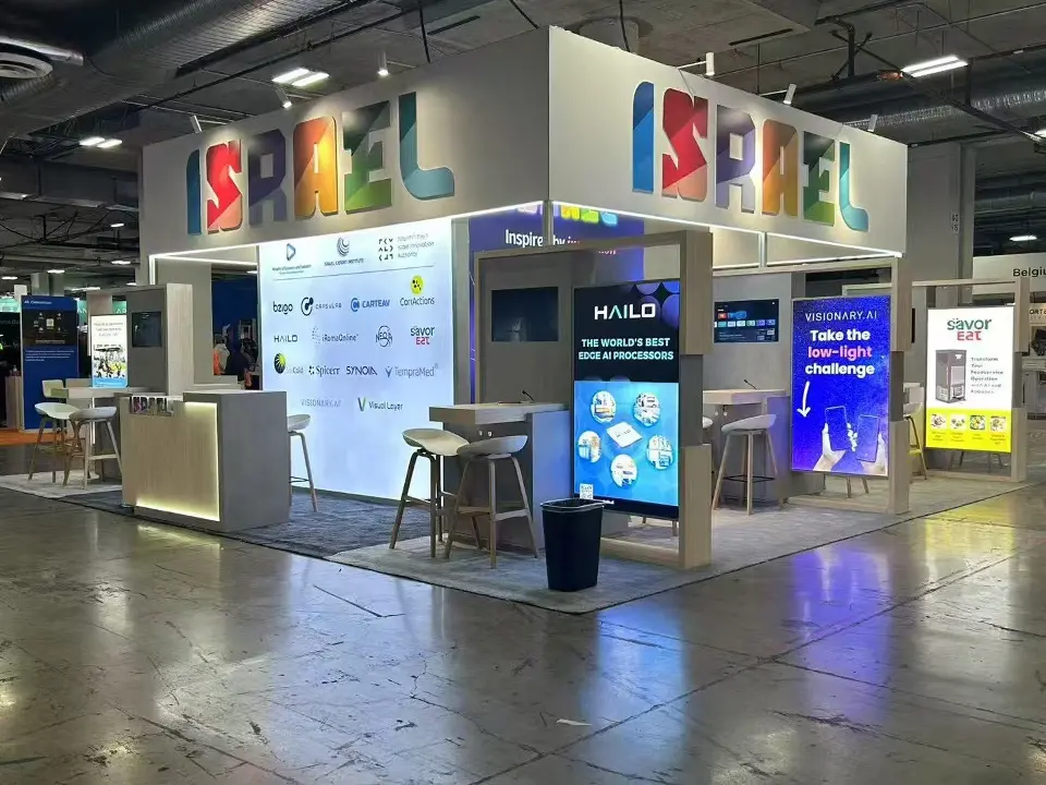 Pavilion booths with lit counters, screens and backlit graphics under ISRAEL lettering