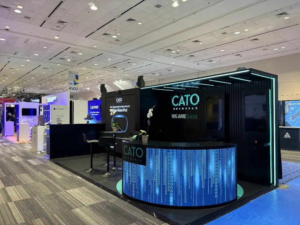 Angled view of Cato Networks booth with curved backlit counter and light strip canopy