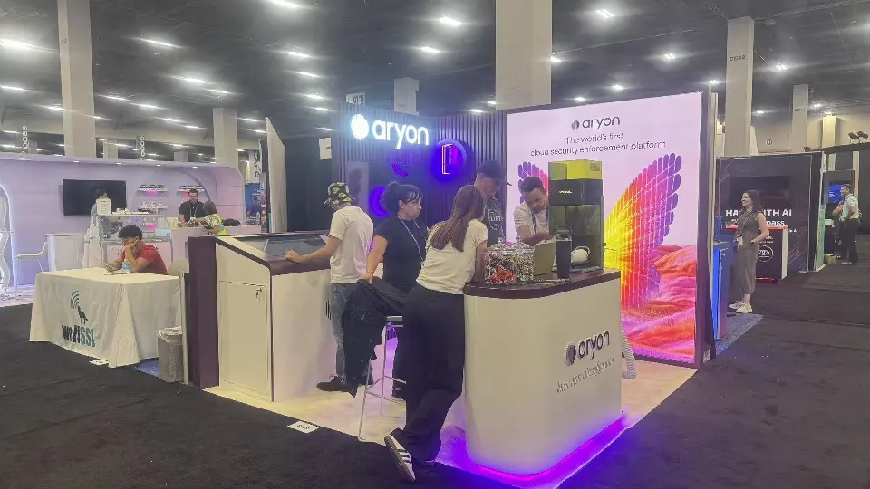 Aryon booth busy with visitors, a white counter and the backlit wing graphic behind