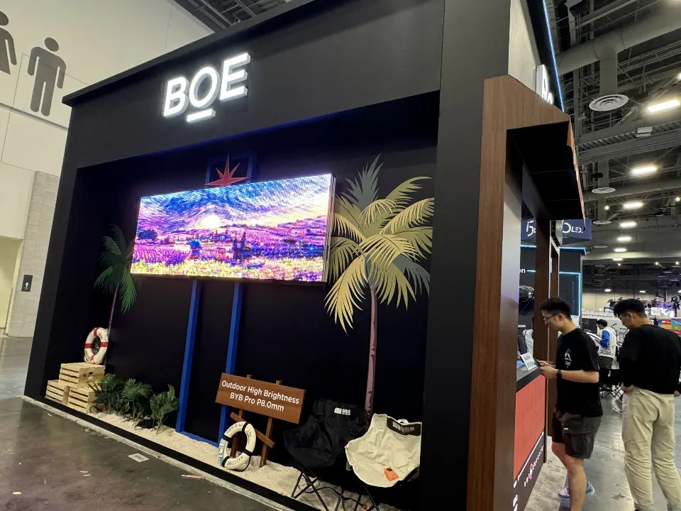 Palm-tree beach scene around a video screen on the black BOE wall