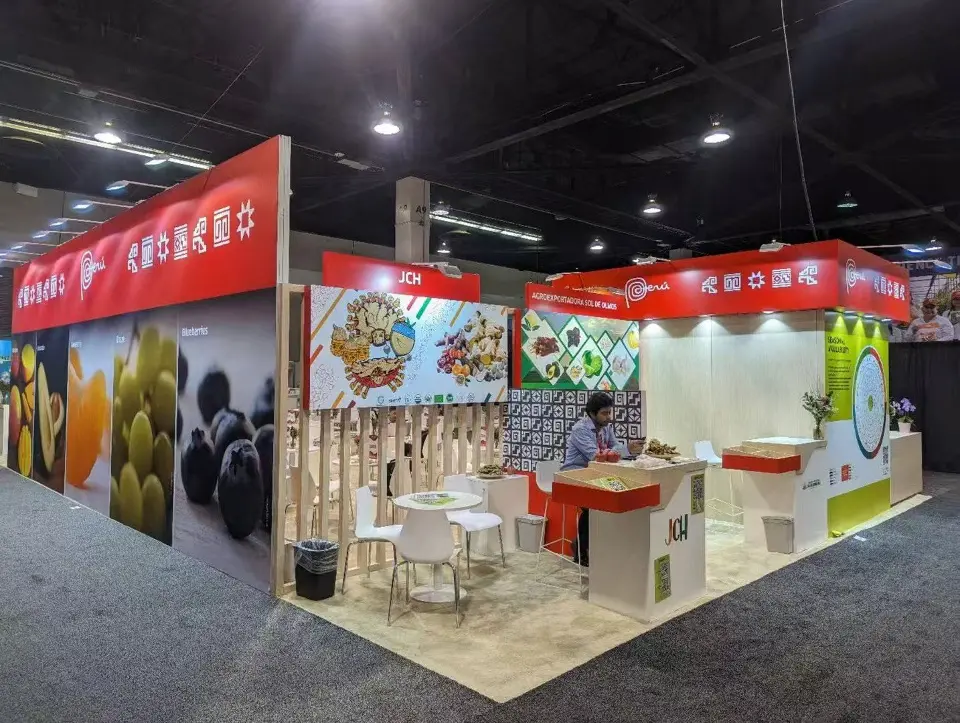 Corner of the Peru pavilion with red fascia, large fruit photo walls and white counters