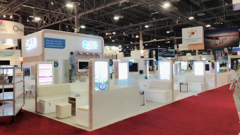 Wide corner view of the white Dubai island booth on a red carpet