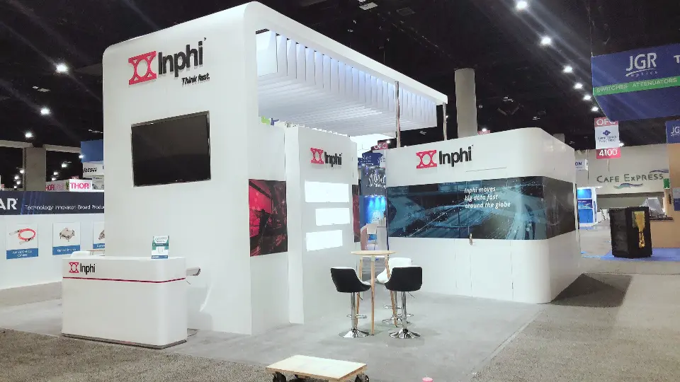 Corner view of the Inphi stand showing wall screen, red graphics and bar seating