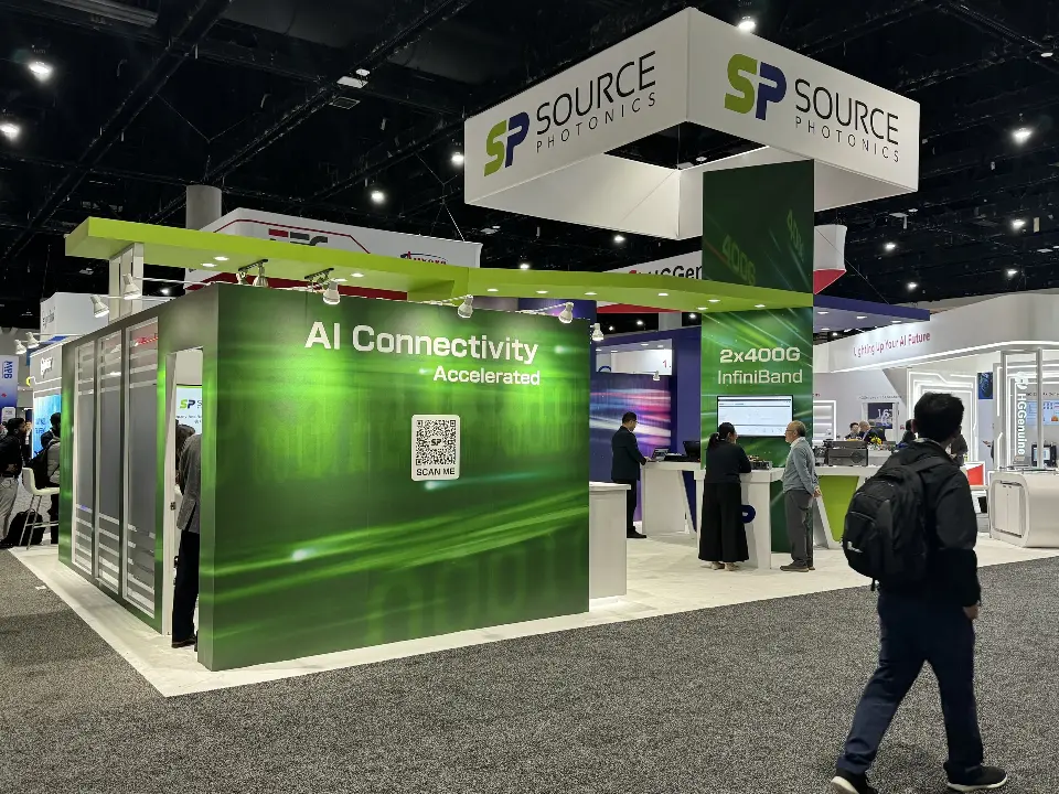 Front of the green graphic walls with visitors walking past the booth