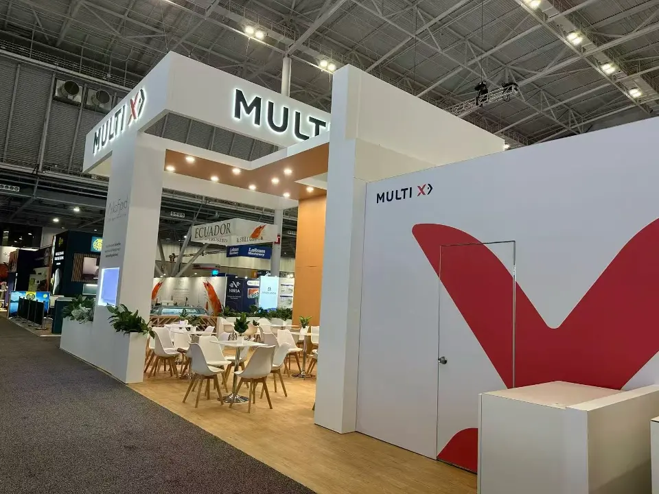 Side of the Multi X booth with a large red V graphic and white cafe seating inside