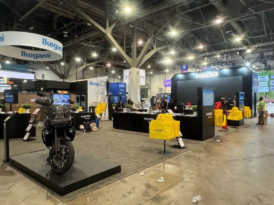 Corner view of the Insta360 booth with a motorbike on a black plinth and yellow bags