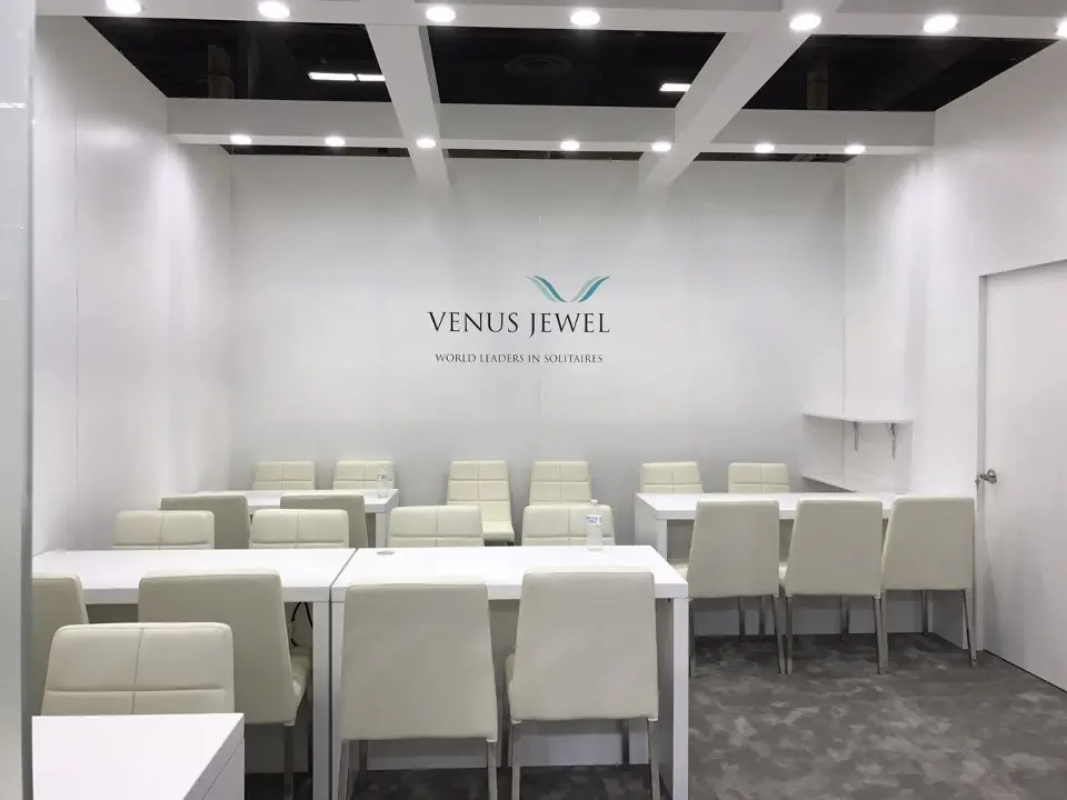 White meeting room with long tables, cream chairs and Venus Jewel wall logo