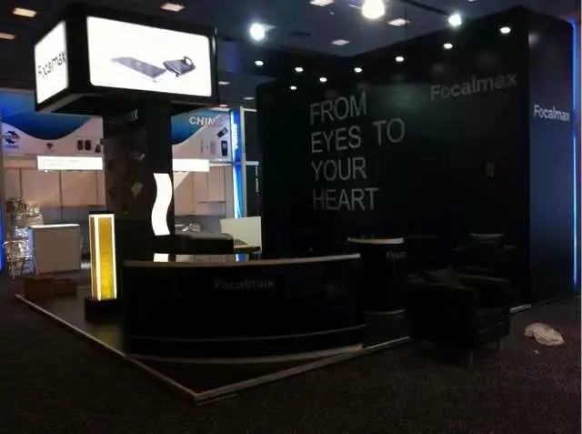 Front angle of curved black Focalmax counters and lounge chairs under the lit lightbox