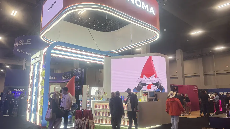 Busy front view with lit arch frames, NOMA header and gnome on the large screen
