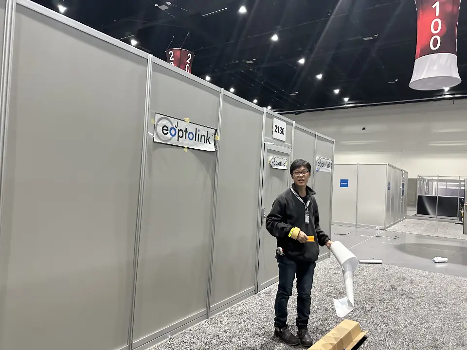 Staff member in front of white enclosed meeting room walls with eoptolink logo