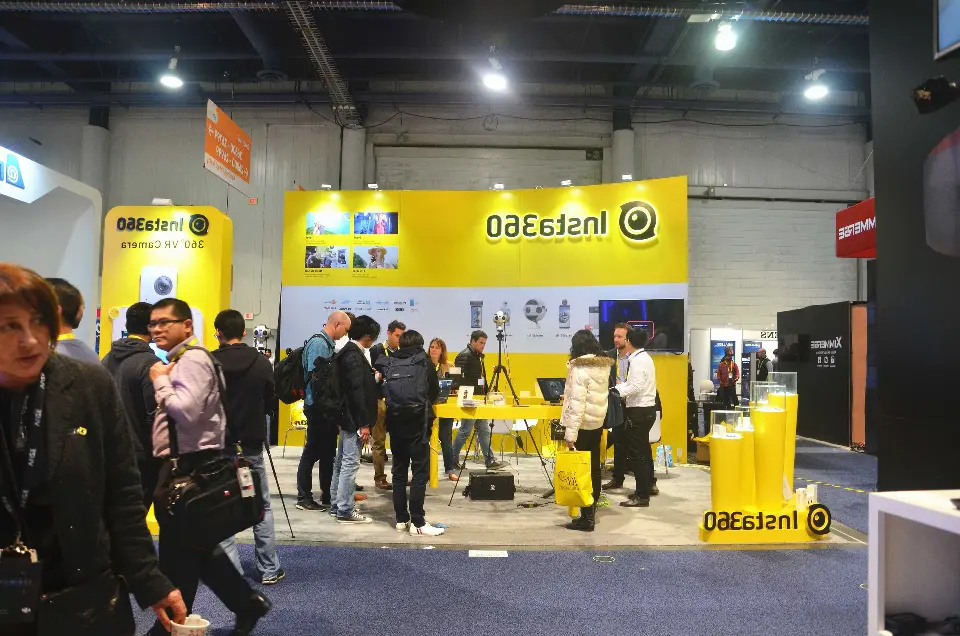 Wide aisle view of the Insta360 booth with visitors and yellow fascia