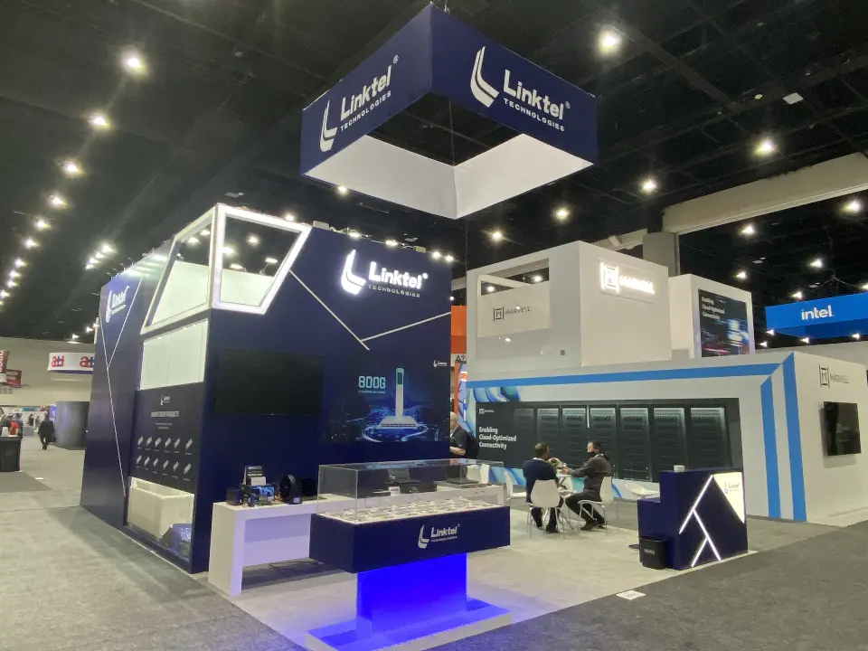 Side angle of Linktel booth showing white stripe graphics, wall screen and seating