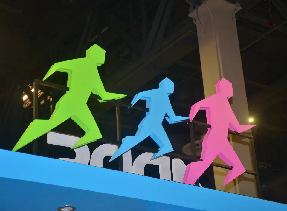 Close-up of green, blue and pink running-figure sculptures on the booth top