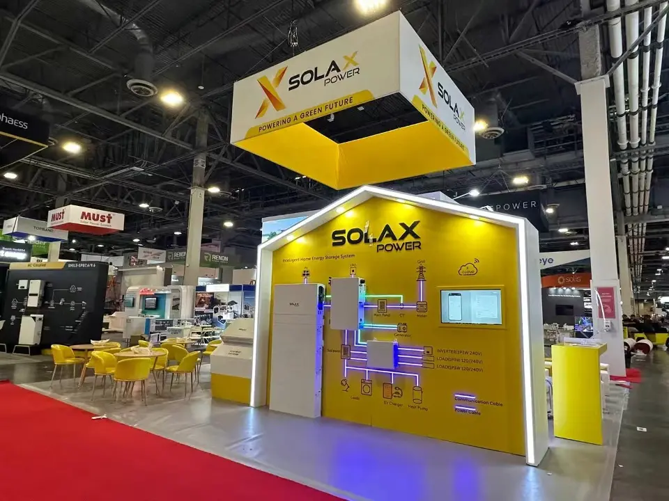 Front view of the SolaX Power house-shaped product wall with lit outline beside yellow chairs and red carpet