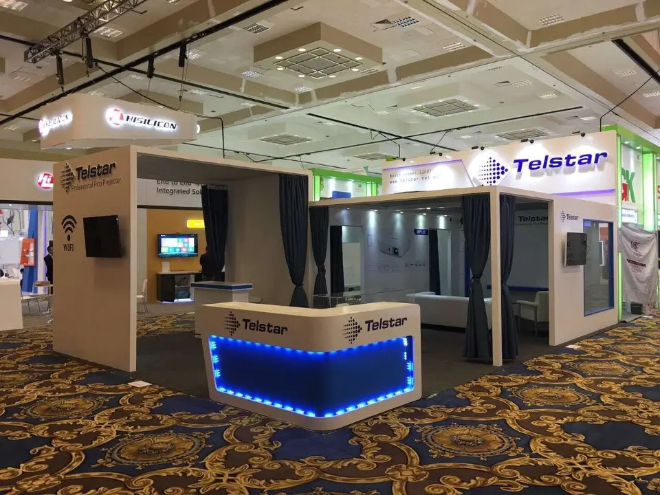 Telstar booth front with blue-lit curved counter and fascia sign on ballroom carpet