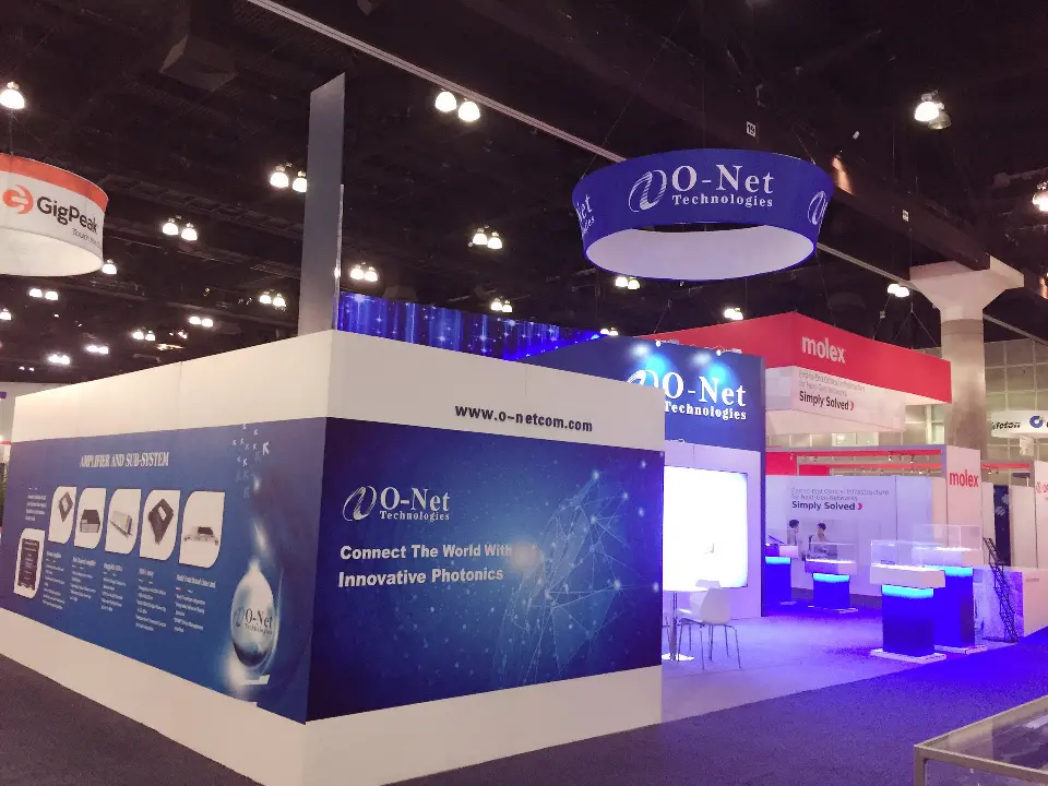 Rear corner of the O-Net booth with blue graphic walls and a lit showcase area