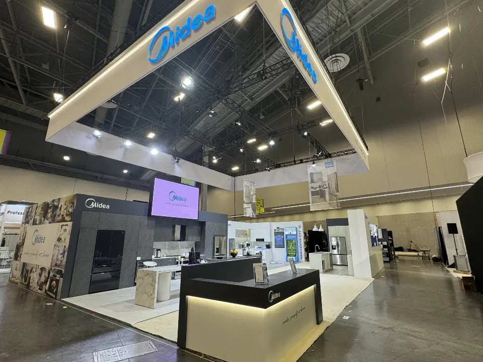 Black reception counter with the Midea logo and a large video screen behind