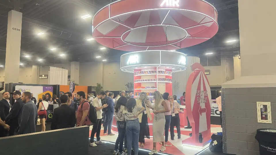 Crowd at the AIR booth with pink tent-shaped feature and ring sign