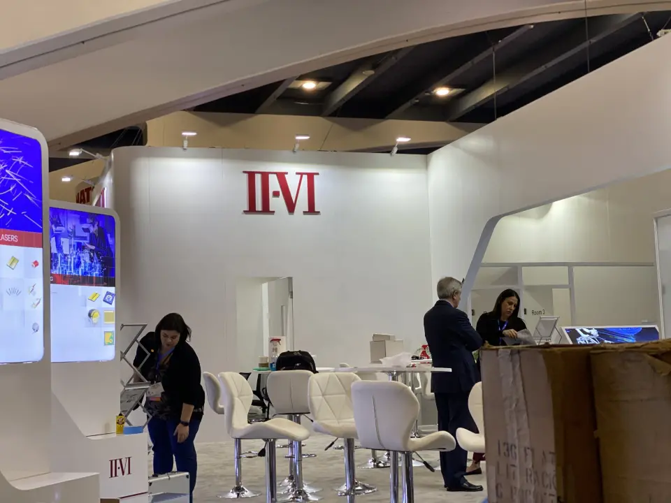 Visitors seated on white stools at the counter beside a lit product screen