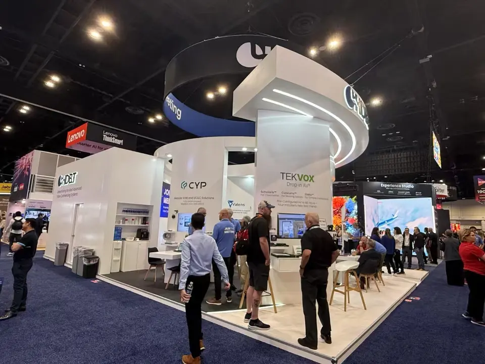 Partner demo side of the HDBaseT Alliance booth with curved white header, branded kiosks and high stools