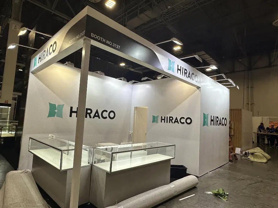 White HIRACO booth with glass showcases and teal logos on three walls