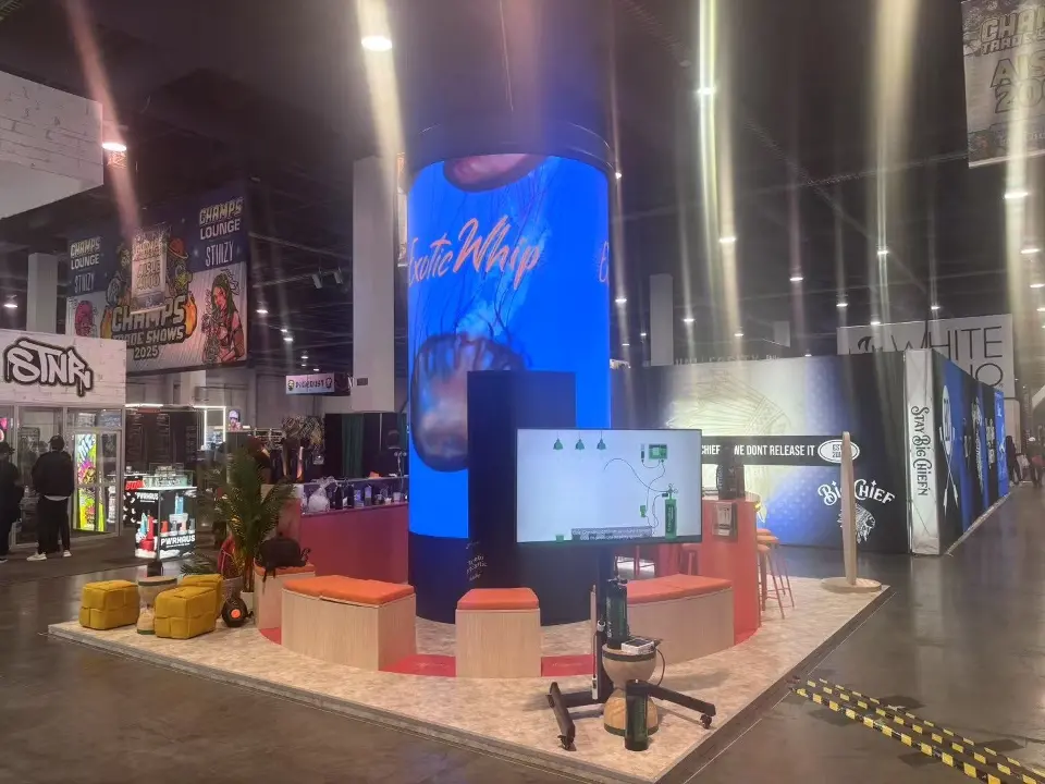 Wide view of the booth with lounge seating and a screen on a stand