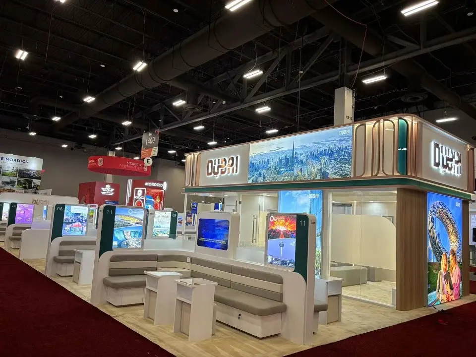 Dubai pavilion corner with backlit city imagery, wood-look cladding and counters