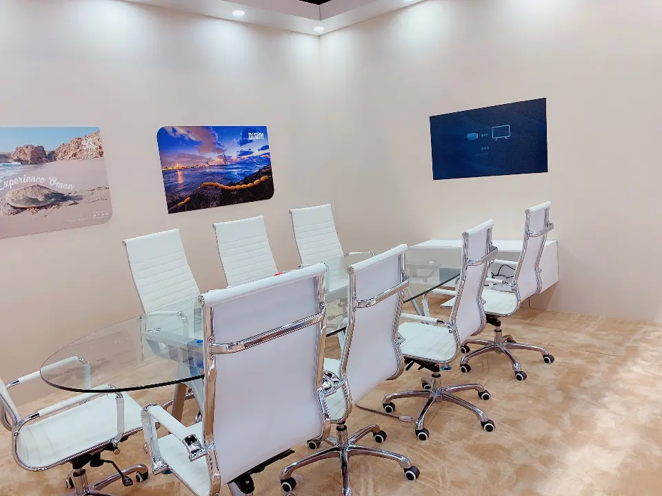 Meeting room with a glass table, white chairs and a wall screen
