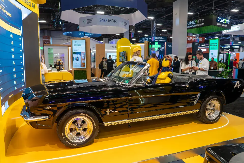 Side view of the classic black convertible parked on the yellow platform inside the booth