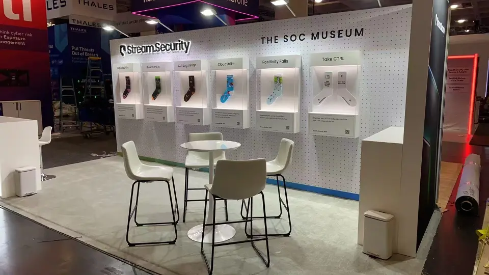 SOC Museum wall of framed socks with white bar stools and a round table at Stream.Security