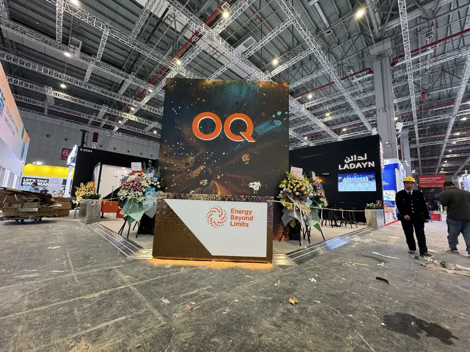 Front view of the OQ tower, welcome counter and lit rear wall from the aisle