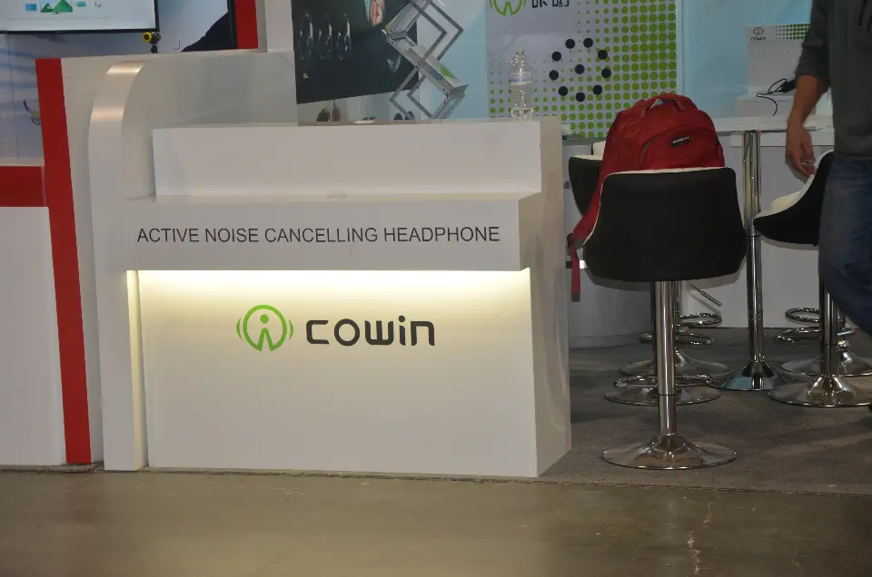 White Cowin counter lit from below, labelled Active Noise Cancelling Headphone, beside bar stools
