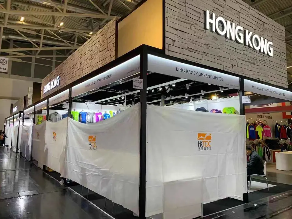 Corner of the pavilion where stone-look and wood-look header panels meet the HONG KONG sign