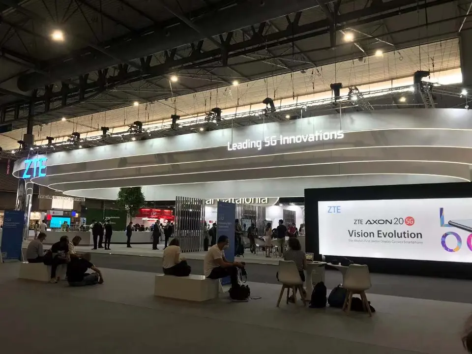 Distant view of the long white canopy with tables and a wide screen