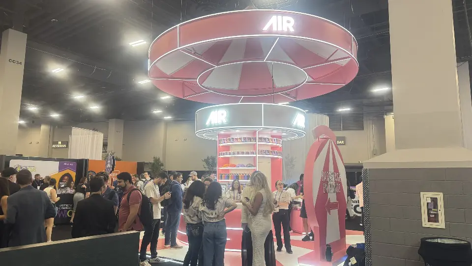 Visitors near the tent feature and pink striped panels of the AIR booth