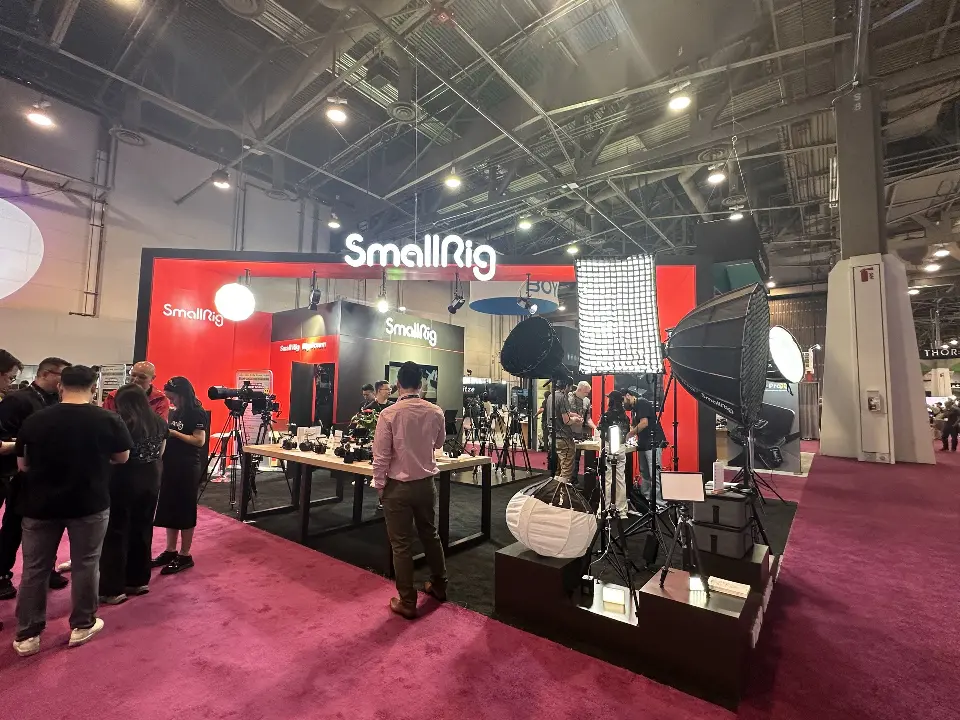 Wider view of SmallRig booth with lighting rigs, product tables and black shelving