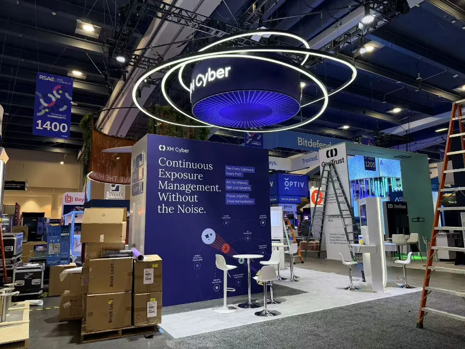 XM Cyber booth with light-ring sculpture over the round sign and tall wall graphic