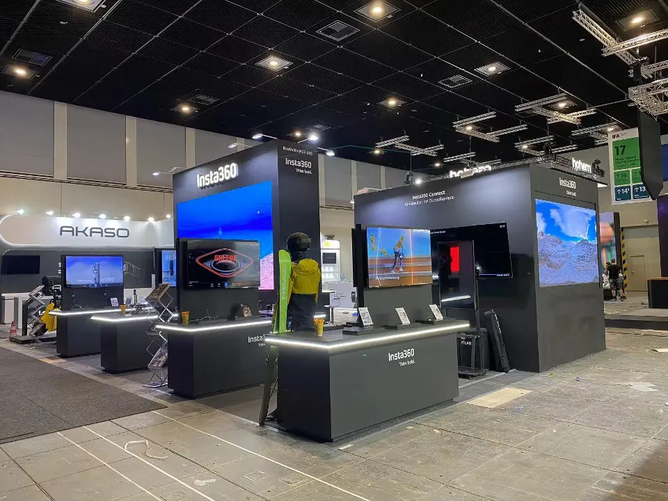 Angle across the stand showing screen towers and lit counters from the opposite corner