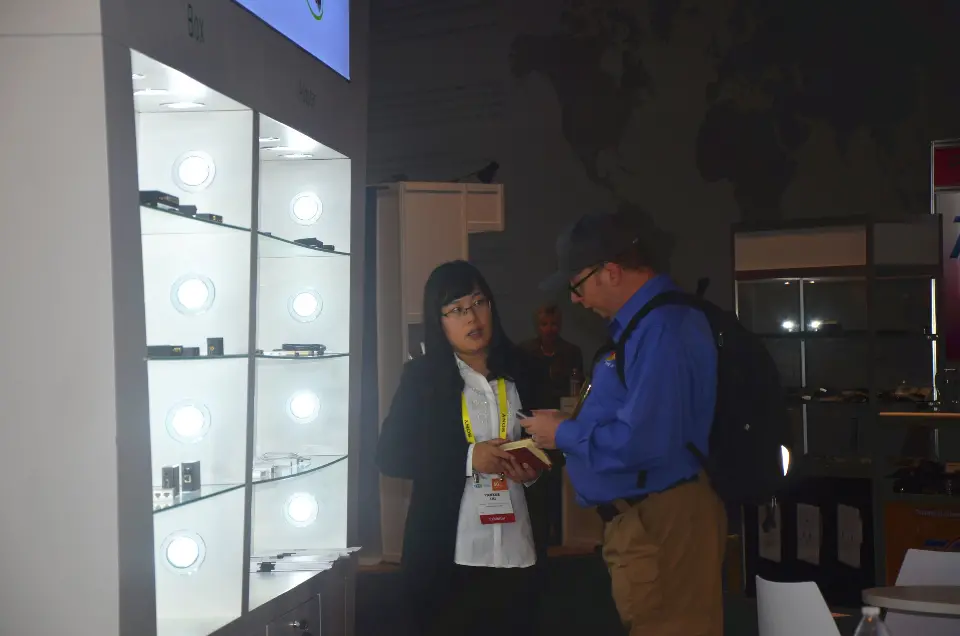 Lit glass shelf cabinet with visitors talking at the side